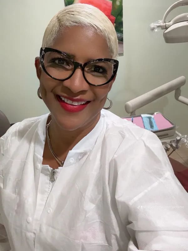 A woman with glasses and white shirt smiling for the camera.