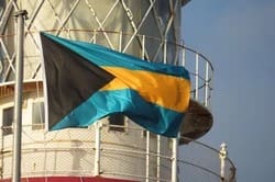 A flag of the bahamas is flying on top of a lighthouse.