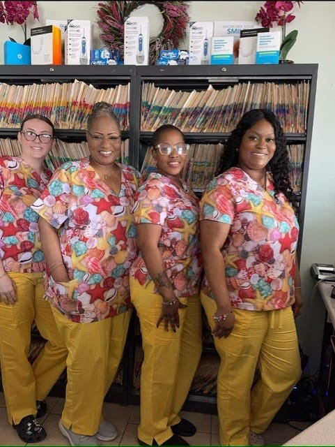 Four women in colorful uniforms smiling.